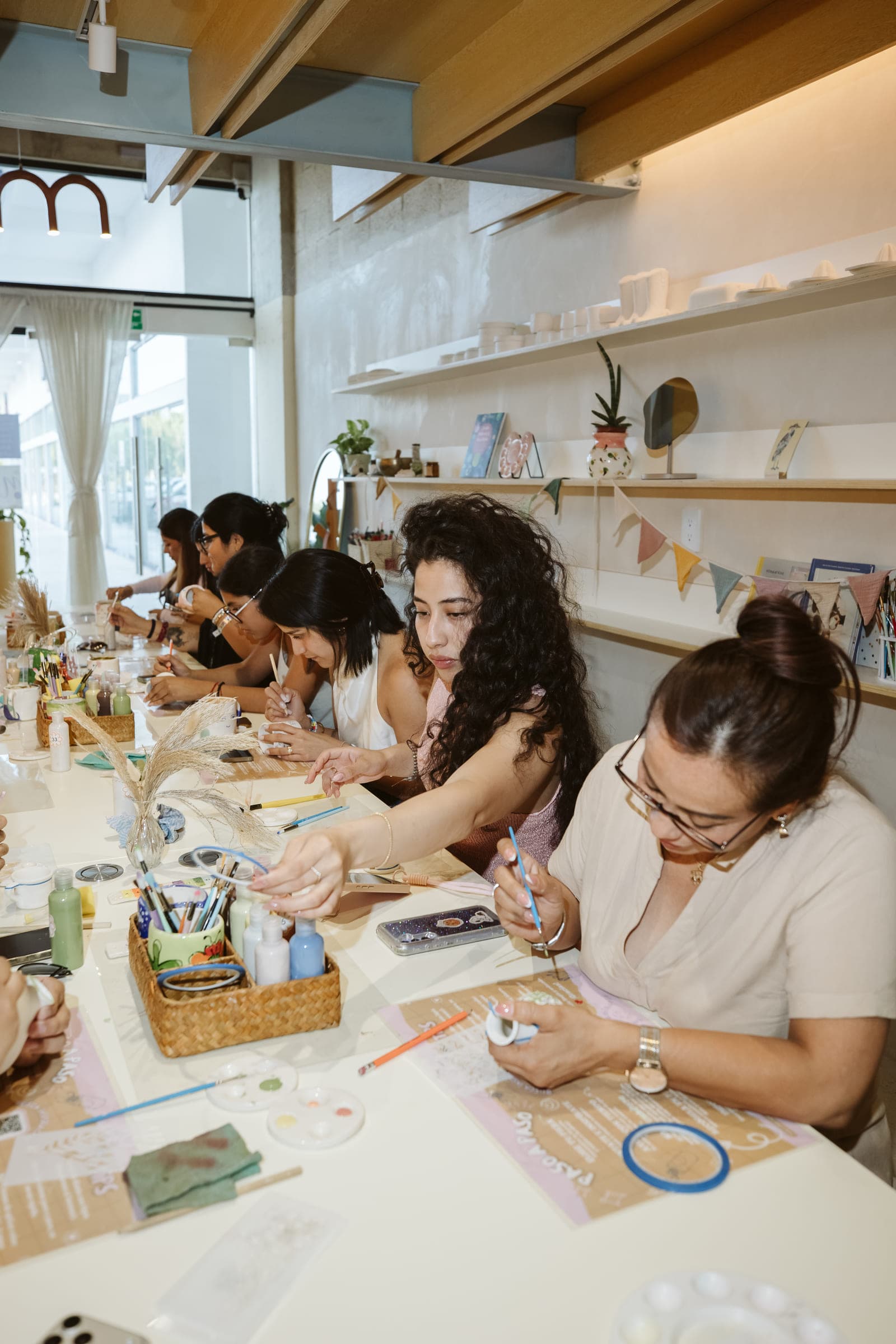 Grupo de personas pintando cerámica en la mesa larga del taller