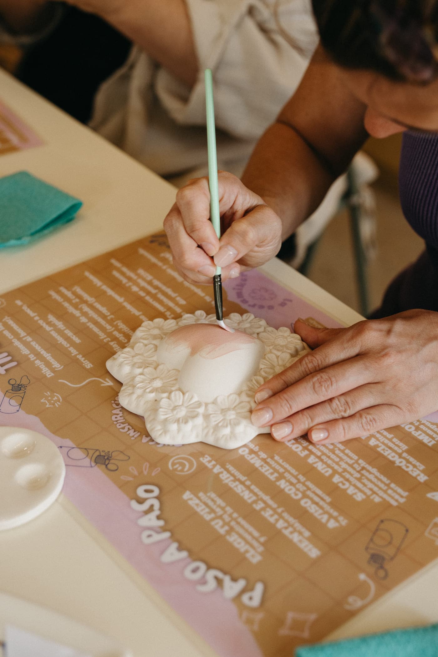 Manos pintando un platito con relieve de flores
