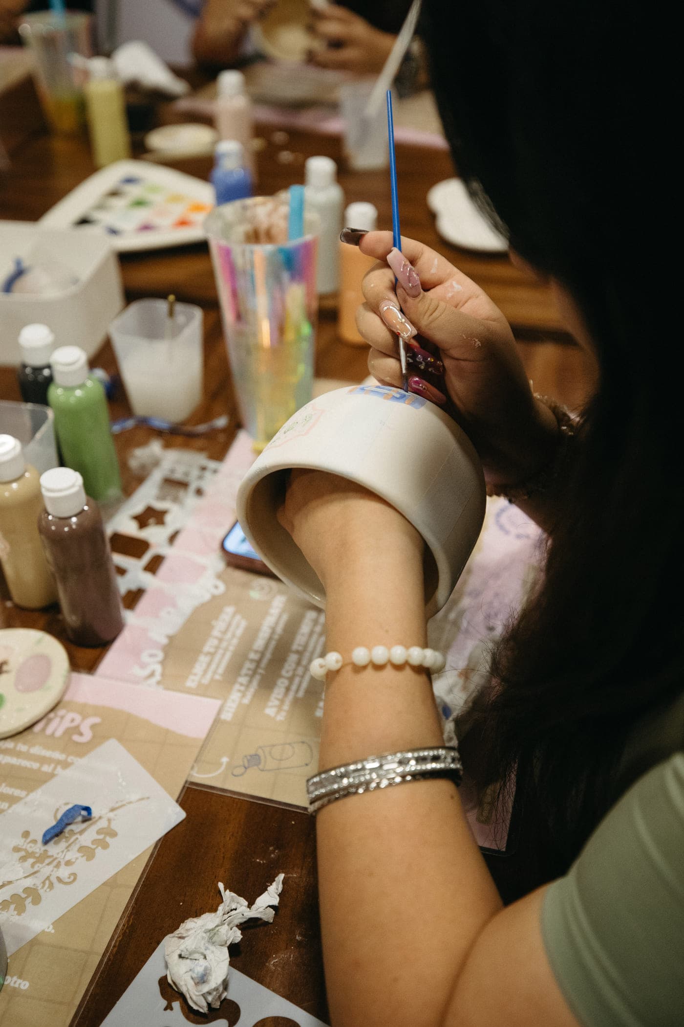 Manos pintando una taza de cerámica con un pincel